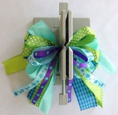 a green and blue bow with polka dots on the front is attached to a metal hook