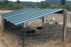 a chicken coop in the middle of a field with two chickens sitting on top of it