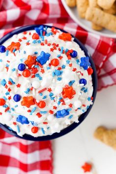 red, white and blue dessert in a bowl on a checkered table cloth next to crackers