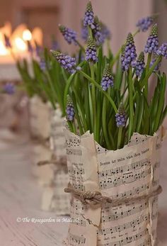 some purple flowers are in small vases with sheet music notes