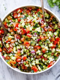 a white bowl filled with cucumber and tomato salad