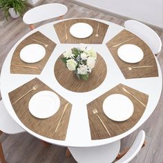 a round table with six chairs around it and a white vase on the center piece