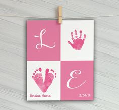 a pink and white baby's handprint with the letter e on it hanging from a clothes line