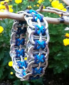 two blue and silver bracelets hanging from a tree branch in front of yellow flowers