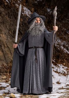 an old man dressed as gandalian holding a staff and wearing a long gray robe