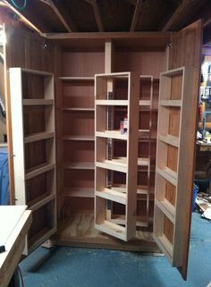 the inside of a wooden bookcase with shelves and doors open in an unfinished room