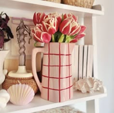 pink flowers in a vase sitting on a shelf next to shells and other decorative items