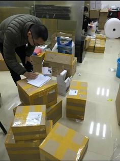 a man standing over boxes in a room with other boxes on the floor and around him