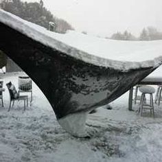 an old boat sitting on top of snow covered ground next to chairs and tablecloths