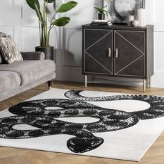 a black and white rug in a living room with a couch, coffee table and potted plant