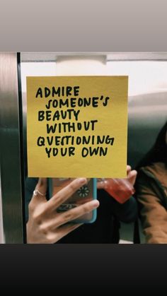 a woman holding up a yellow sign that says admire someone's beauty without questioning your own