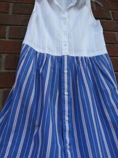 a blue and white striped dress hanging on a brick wall