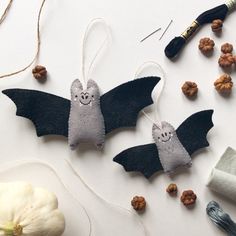 two bats hanging from strings next to some nuts and thread on a table with other items