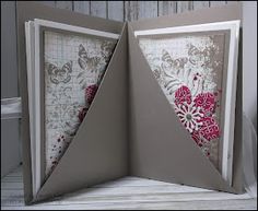 an open card with some flowers and butterflies on it's side, in front of a wooden background