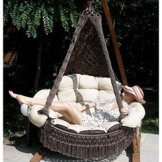 a woman laying on top of a swing chair