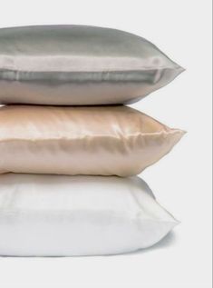 three pillows stacked on top of each other in front of a white background with the same color