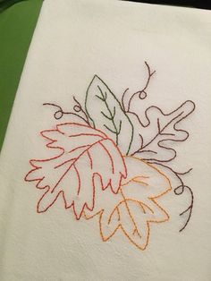 a white towel with embroidered leaves on it