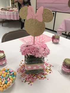 a minnie mouse centerpiece on top of a table with pink and gold confetti