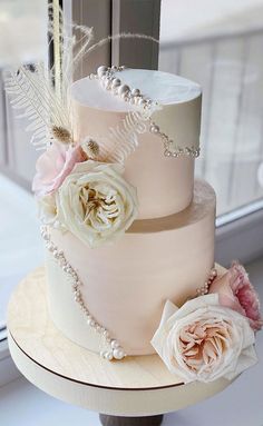 a three tiered wedding cake with flowers and feathers