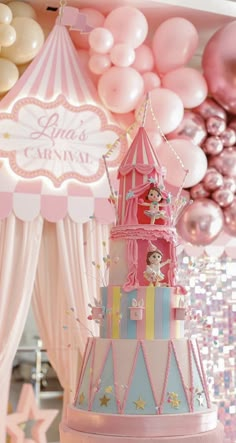 there is a pink and blue castle cake on the table with balloons in the background