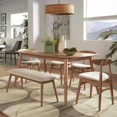 a dining room table with chairs and a bench in front of the window, next to a potted plant