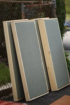 three wooden panels sitting next to each other in front of a fence