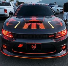 a black sports car with red and yellow designs on it's hood, parked in a parking lot