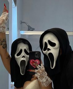 two people in halloween costumes are taking a selfie with their cell phone while wearing masks