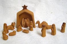 a group of wooden toys sitting on top of a white sheet covered floor next to a nativity scene