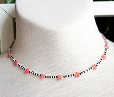 a white mannequin with a black and pink beaded necklace on it's neck