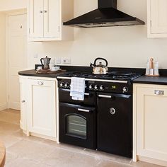 a black stove top oven sitting inside of a kitchen next to white cabinets and counter tops