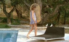 a woman walking past a pool with a bird cage on it's back end