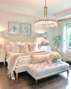 a bedroom with white furniture and chandelier hanging from the ceiling, along with pictures on the wall