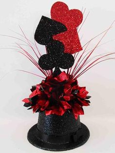 a black hat with red flowers and two hearts on the top, sitting in front of a white background