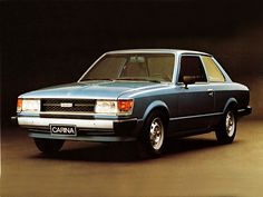 an old blue station wagon parked in front of a black background