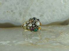 "Vintage Yellow and White Gold Multi Stone \"Thai\" Cocktail Ring stamped 18K , sits 5/8\" off finger, 3mm central stone, round diamonds alternating semi precious pear shaped cabochons, tiger eye, citrine, green onyx, ruby, moonstone, tourmaline, sapphire, garnet, 19 diamonds, Ring size 8, Circa 1950, weight 9.43 grams Stock # BRT134R07 Most rings are sizable for a small fee. If the ring you are considering is the incorrect size contact us for a quote. This listing contains photographs of the ac Gold Coin Ring, Sparkly Ring, Gold Diamond Band, Coin Ring, Diamonds Ring, Fine Jewelry Designers, Green Onyx, Blue Topaz Ring, Multi Stone