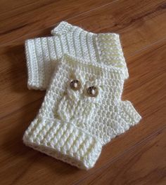 two crocheted baby sweaters with buttons on the front and bottom, sitting on a wooden floor