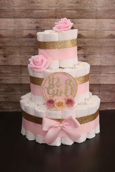 a pink and gold diaper cake with roses on top is sitting on a table