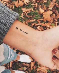 two people holding hands with the word love tattooed on their wrist and one has a small heart