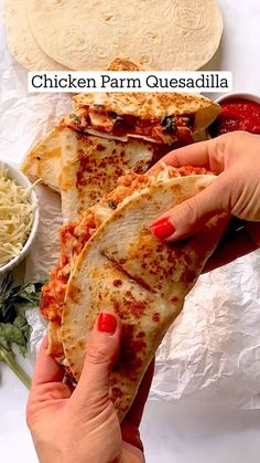 a person holding a chicken farm quesadilla in front of some other food