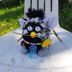 a small stuffed animal sitting on top of a white chair with a flower in it's mouth