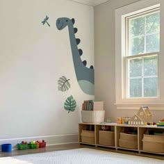 a child's room with a dinosaur wall decal and toy storage bins