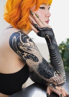 a woman with orange hair and tattoos on her arm