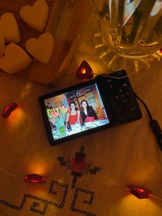 a cell phone sitting on top of a table next to candles and hearts in the background