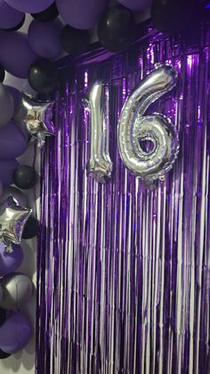 balloons and streamers are arranged around the number sixteen balloon wall in this purple room