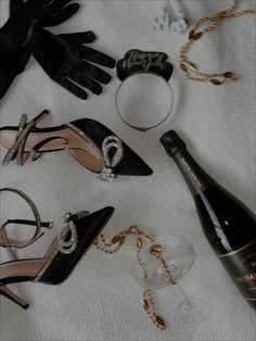 several different types of shoes and accessories on a white cloth next to a bottle of wine