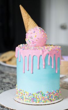 a blue cake with sprinkles and an ice cream cone on the top