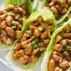 lettuce wraps filled with chicken and sauce on a white plate, ready to be eaten