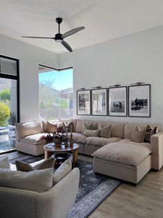 a living room filled with furniture and a large window covered in pictures on the wall