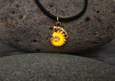 a yellow flower pendant sitting on top of a rock